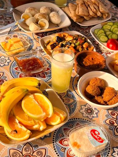 una mesa con platos de comida y un vaso de jugo de naranja en Tasneem Palace, en Luxor