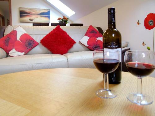 a bottle of wine and two glasses on a table at Ysgubor Uchaf - 29517 in Fairbourne