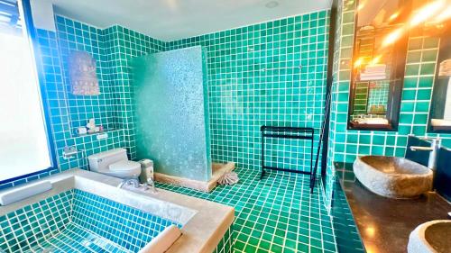 La salle de bains est pourvue de carrelage bleu, d'une baignoire et de toilettes. dans l'établissement Montra Resort, à Nathon Bay