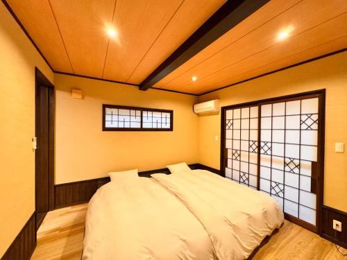 a bedroom with a bed in a room with a window at Ryokan YUFUMOMIJI in Yufuin