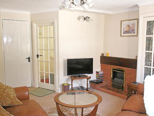 a living room with a tv and a fireplace at Flagstaff Cottage in Robin Hood's Bay