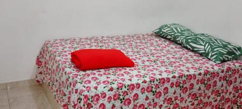 a bed with a red pillow on top of it at Casa do sossego - conforto, praia, piscina in Maricá