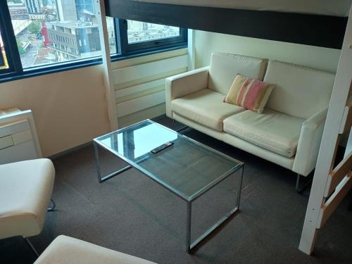 a living room with a couch and a glass table at Cozy 1 Bed Apartment - 2 Min to Queen VIC Market in Melbourne