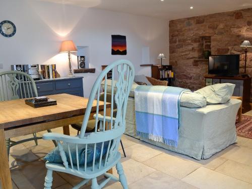 a living room with a table and chairs and a bed at The Barn in Greystoke