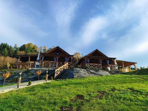 Un par de casas de troncos en una colina cubierta de hierba en Chatka Niedźwiadka, en Bezmichowa Dolna