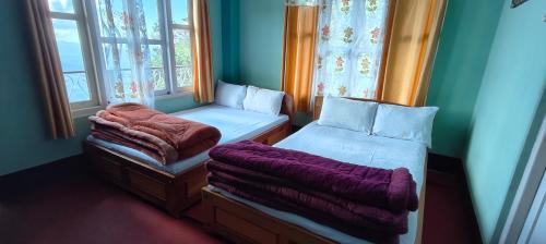 a bedroom with two beds and two windows at Chander Pahar Retreat in Kalimpong