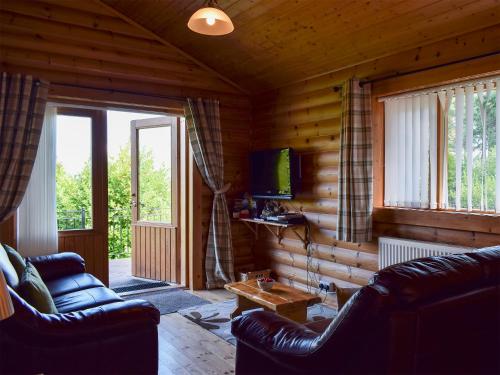 a living room with two couches and a television in a log cabin at Fingask Log Cabin - S4394 in Glenfarg