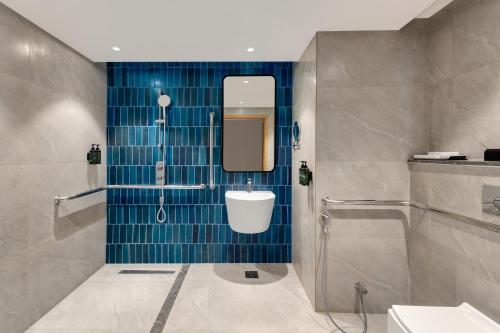 une salle de bains avec douche et toilettes et carrelage bleu dans l'établissement Ramada Encore by Wyndham Rajbagh Srinagar, à Srinagar