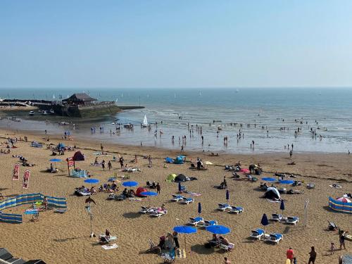 a group of people on a beach with umbrellas at Viking Bay Apartment in Broadstairs