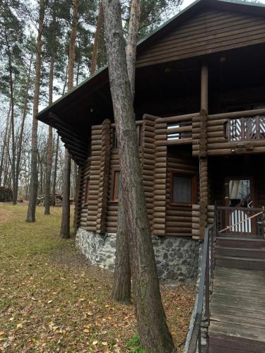 a log cabin in the woods with a wooden porch at Готельно-ресторанний комплекс Загадка in Khmelʼnytsʼkyy