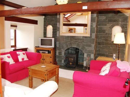 a living room with pink furniture and a fireplace at Gill Barn in Bampton