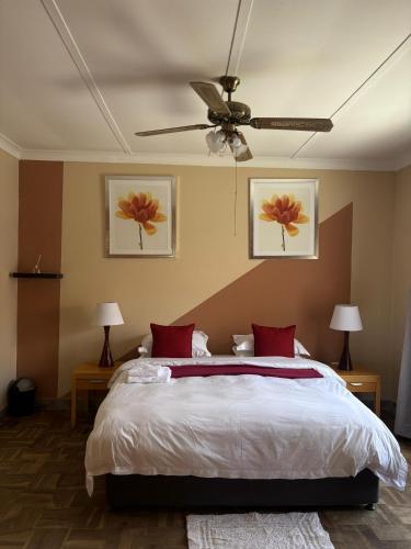 a bedroom with a bed and a ceiling fan at Laroza guest house in Rustenburg