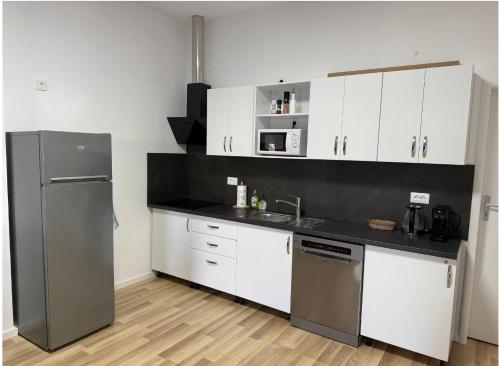 a kitchen with white cabinets and a stainless steel refrigerator at Palita Vita - Durrës Beach in Durrës