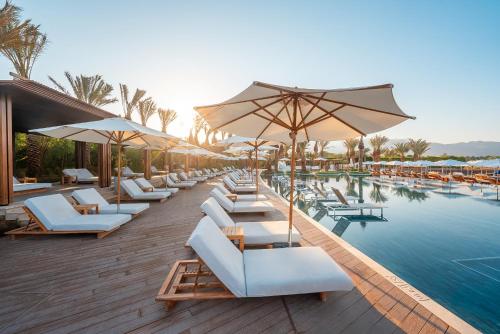 een zwembad met witte ligstoelen en parasols bij Hyatt Regency Aqaba Ayla Resort in Aqaba