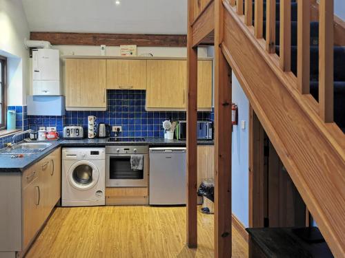 Una cocina con armarios de madera y una escalera en una casa. en Blue Charm - 29585, en Damerham