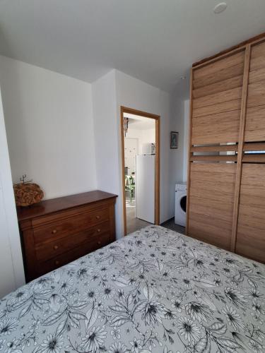 a bedroom with a bed and a dresser and a refrigerator at Gîte du Papillon CALUTRE in Carvin