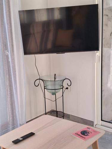 a flat screen tv on a wall with a table at Gîte du Papillon CALUTRE in Carvin