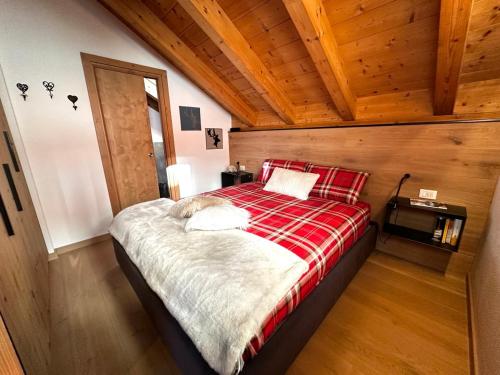 a bedroom with a bed with a red and white blanket at Appartamento Picchio in Bormio