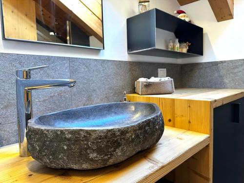 a large rock bath tub sitting on a wooden counter in a bathroom at Appartamento Picchio in Bormio