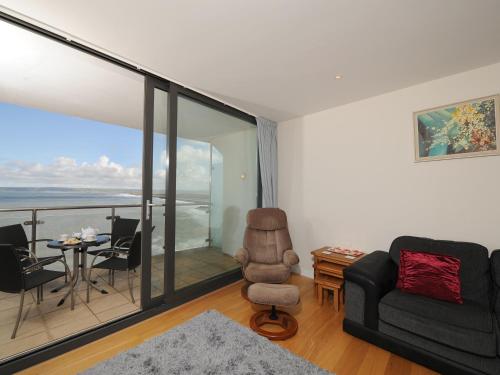 a living room with a couch and a chair and a balcony at Tidal Bay in Westward Ho