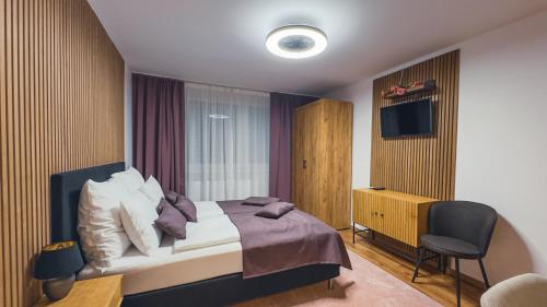 a bedroom with a bed and a chair and a television at Apartmán Astana in Levoča