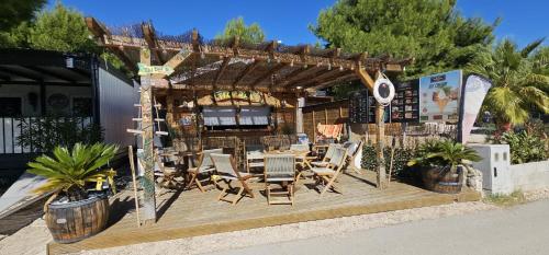 a restaurant with a table and chairs on a wooden deck at Maui, Kamp Heron, Drage, Croatia in Drage