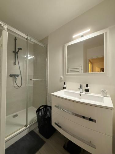 een witte badkamer met een wastafel en een douche bij Le Monde des Dunes - T3 - Parking privé in Angers