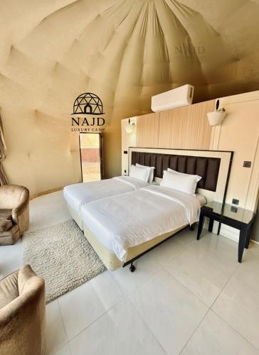 a bedroom with a king sized bed and a chair at Najd Luxury Camp in Wadi Rum