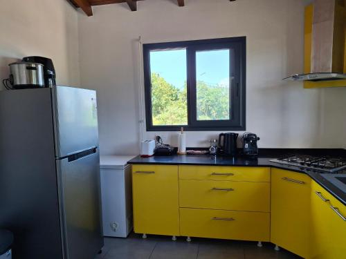a kitchen with yellow cabinets and a window at Haut de maison T4 à Petit Canal in Petit-Canal