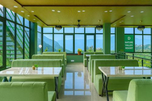 a restaurant with tables and chairs with mountains in the background at Doon Nature Valley Resort, Mussoorie in Mussoorie
