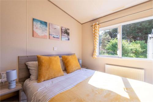 a bedroom with a bed with yellow pillows and a window at 3 Bedroom Caravan-Seton Sands in Port Seton