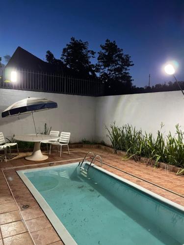 een zwembad met een tafel en een parasol bij Casa em Aguas de Lindoia - Próxima ao balneário e da praça principal in Águas de Lindóia