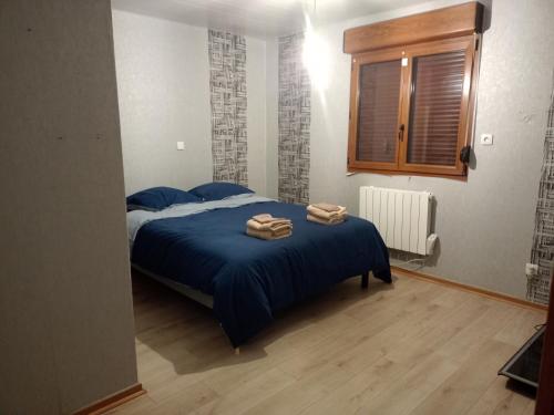a bedroom with a blue bed with towels on it at Gîte du Tronquoy in Aix-en-Ergny