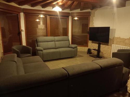 a living room with a couch and a chair and a television at Gîte du Tronquoy in Aix-en-Ergny
