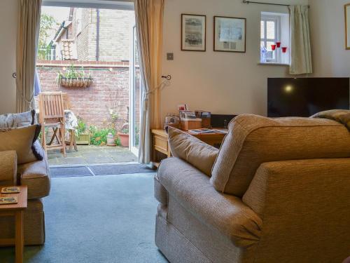 ein Wohnzimmer mit Sofa und Fernseher in der Unterkunft Trentham Cottage in Snettisham