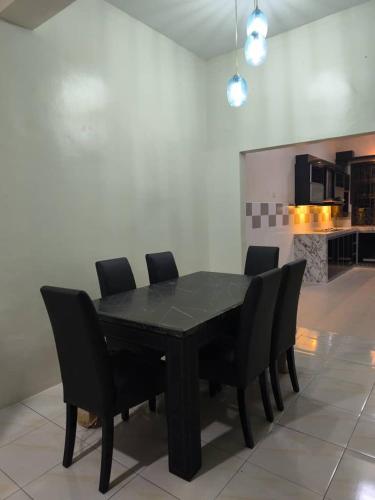 a black dining room table with black chairs in a kitchen at Coach homestay 2 in Kuantan