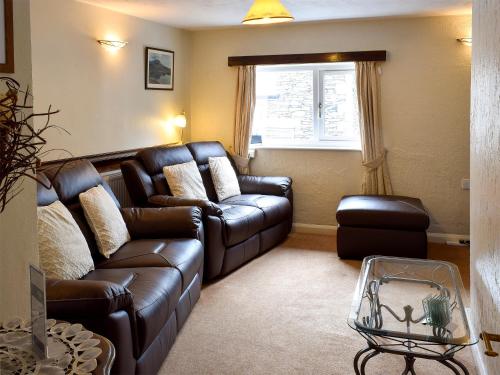 a living room with a leather couch and a window at Nu-Holme in Windermere
