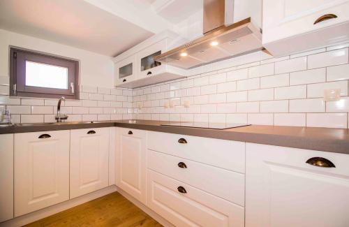 a white kitchen with white cabinets and a window at Mystras 2 Residences Upper and Ground Floor in Mystras