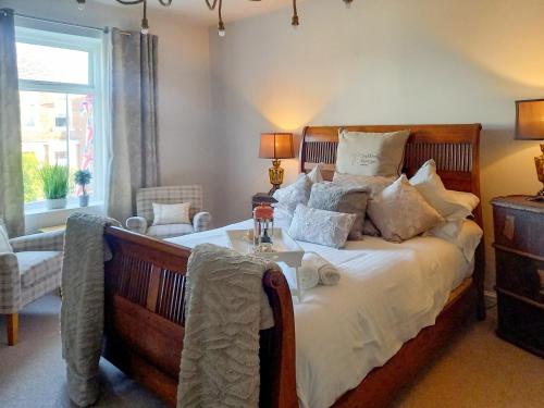a bedroom with a large bed with white sheets and pillows at The Saddler Cottage in East Boldon