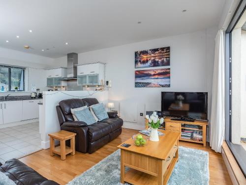 ein Wohnzimmer mit einer Ledercouch und einem Tisch in der Unterkunft Sand Dunes in Westward Ho