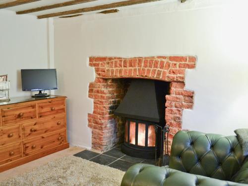 ein Wohnzimmer mit gemauertem Kamin und Fernseher in der Unterkunft Rose Cottage in Hythe