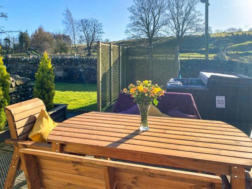 a wooden table with a vase of flowers on a patio at Lily Rose Cottage in Lanercost