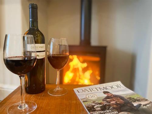 een fles wijn en twee glazen op een tafel bij Hollyhock in Tavistock