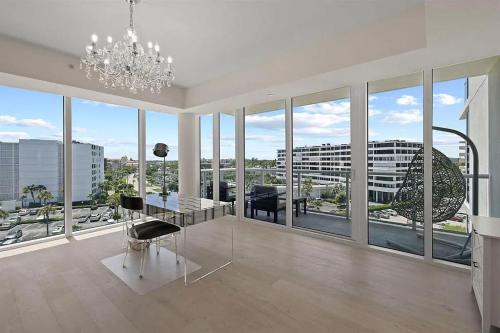 een eetkamer met een kroonluchter en grote ramen bij Chic Three-Bedroom Oceanfront Apartment with Stunning Views in South Palm Beach