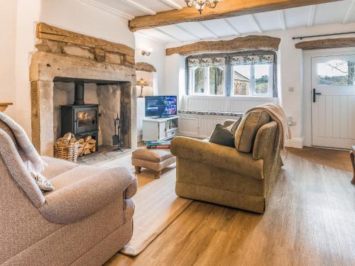 a living room with two chairs and a fireplace at Lodge Farm Cottage in Haworth