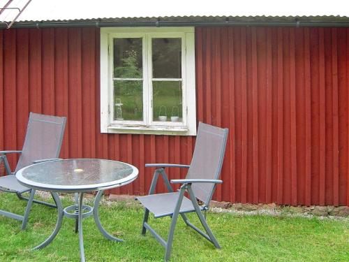 een tafel en stoelen voor een rode muur bij 6 person holiday home in Osby-By Traum in Osby