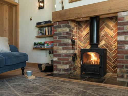 ein Wohnzimmer mit einem Kamin und einem blauen Sofa in der Unterkunft Daisy in Scruton