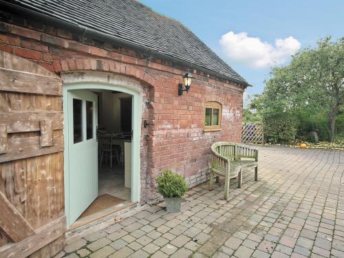 a brick building with an open door and a bench at Groom's Cottage - E5398 in Dunstall
