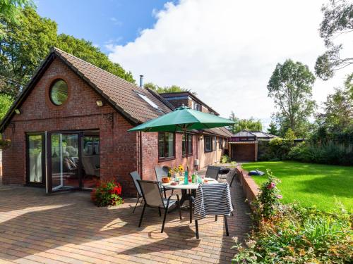 a patio with a table and a green umbrella at Woodlands in Milverton