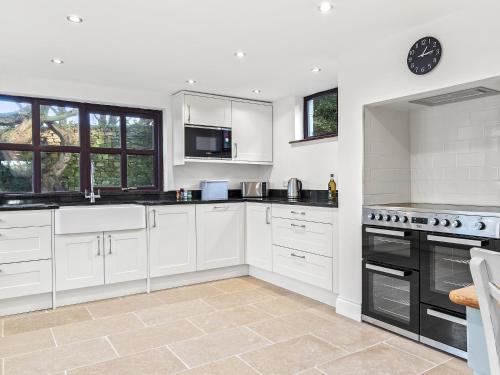 a kitchen with white cabinets and black appliances at Morfa Ganol in Llangranog